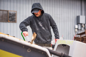 Cleaning a dirty drift boat in the Fusion Apex Hoody from Skwala Fishing.