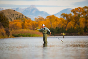 Checking for cracks in his fly rod while wading a Montana river in the Carbon Waders from Skwala Fishing. 