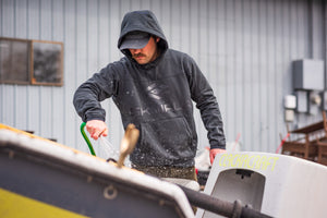 Cleaning a dirty drift boat in the Fusion Apex Hoody from Skwala Fishing. 